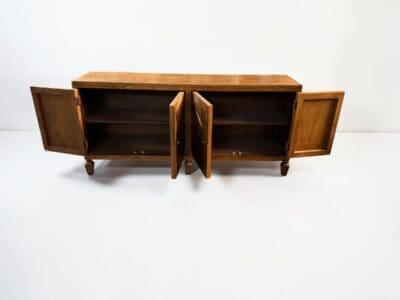 Wooden sideboard with two open doors showing interior shelves against a pale background.