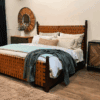 Handcrafted leather bed with woven leather headboard and footboard in a modern rustic bedroom setting, paired with wood nightstand and neutral bedding