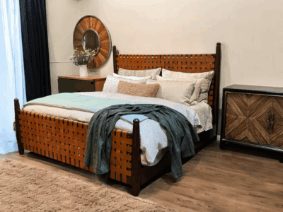 Handcrafted leather bed with woven leather headboard and footboard in a modern rustic bedroom setting, paired with wood nightstand and neutral bedding